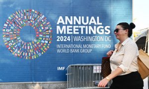 Una persona pasa junto a uno de los carteles que anuncia la Asamblea Anual del FMI y del Banco Mundial, en su sede en Washington. AFP/Mandel Ngan