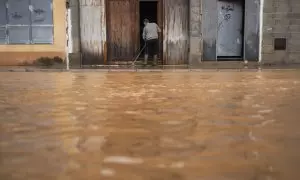 Un hombre limpia el barro de su entrada, a 29 de octubre de 2024, en Llombai, en el País Valencià.