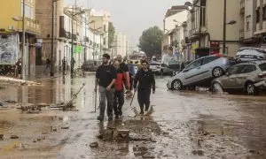 Varias personas recorren calles llenas de agua y barro tras el paso de la DANA por el barrio de La Torre de València, a 30 de octubre de 2024.