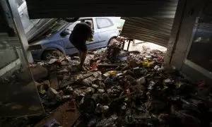 Una persona intenta recoger alimentos de una tienda en València, tras las fuertes lluvias causadas por la DANA