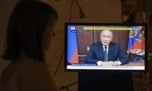 Una mujer mira un discurso televisado del presidente ruso Vladimir Putin, en Moscú, Rusia.