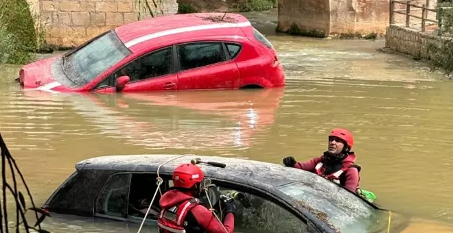 Los bomberos comienzan a extraer del cauce del río los coches arrastrados por el agua en Alcalá del Júcar