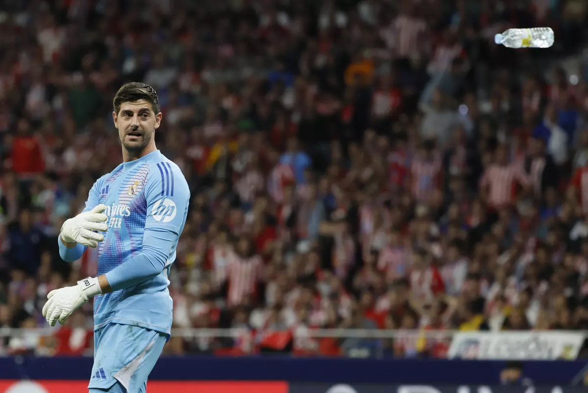 El portero del Real Madrid Thibaut Courtois retira una botella de agua lanzada desde la grada durante el partido de la LaLiga EA Sports que Atlético de Madrid y Real Madrid disputaron este domingo en el estadio Civitas Metropolitano. — Ballesteros / EFE